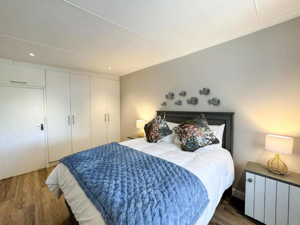 Spacious bedroom with queen bed, blue quilt, decorative pillows and wall art