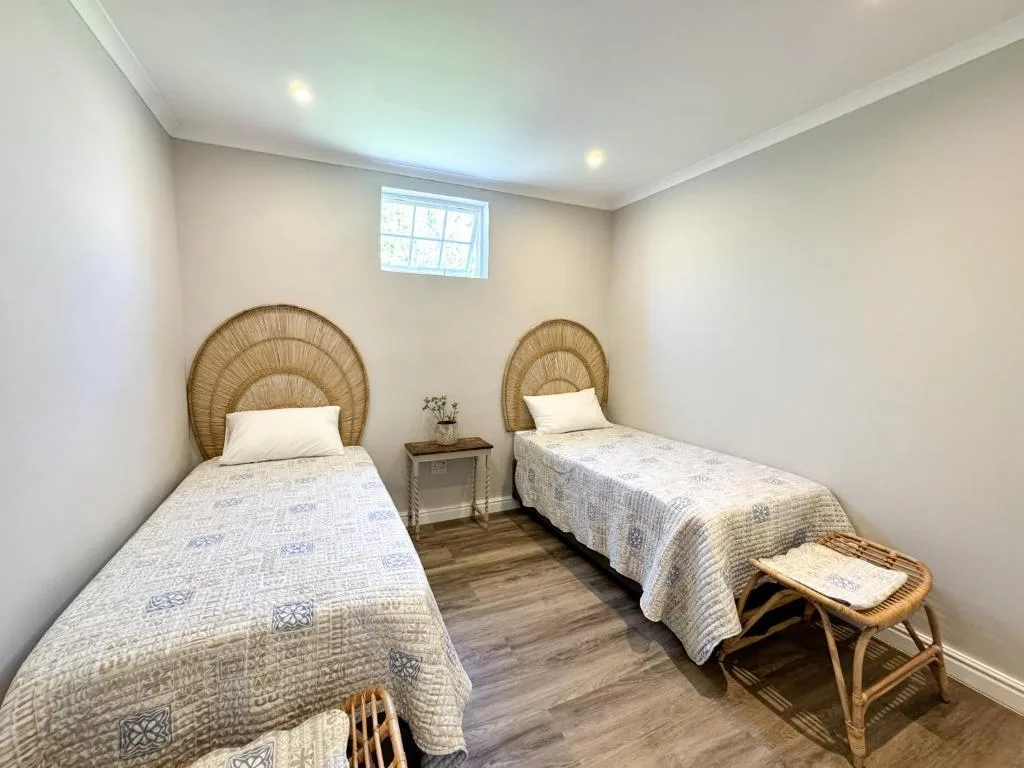 Twin bedroom with wicker headboards and neutral bedding, well-lit