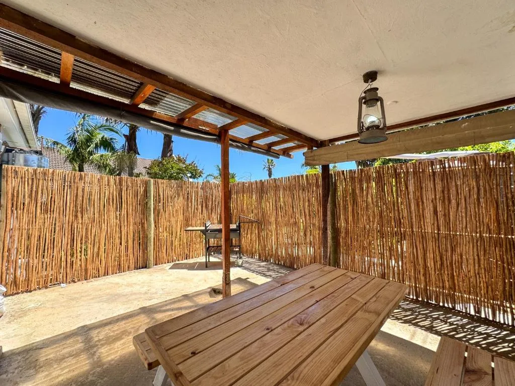 Spacious covered patio with wooden pergola, dining table, and reed fencing