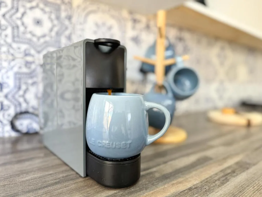Close-up of modern coffee maker with blue Le Creuset mug on wooden table