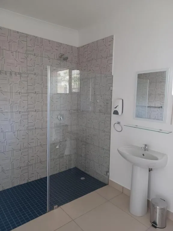 Modern bathroom with walk-in shower, pedestal sink, and mirror