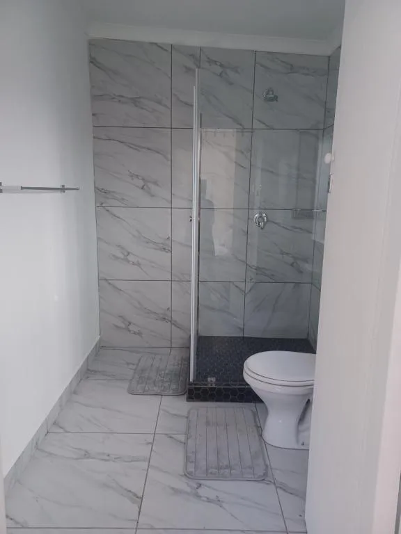 Modern bathroom with marble-tiled walk-in shower and white toilet