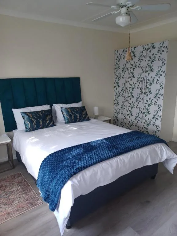 Bedroom with teal upholstered bed, white linens, blue throw blanket, and patterned wardrobe