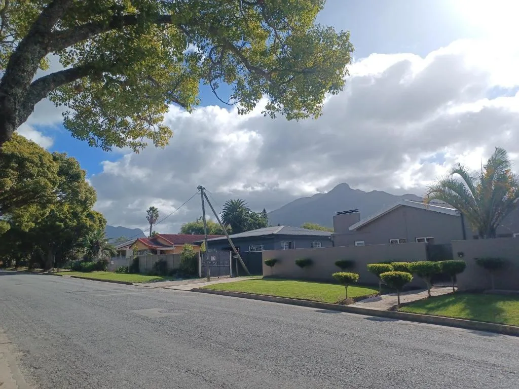 Modern brown cottage with manicured gardens and mountain backdrop visible