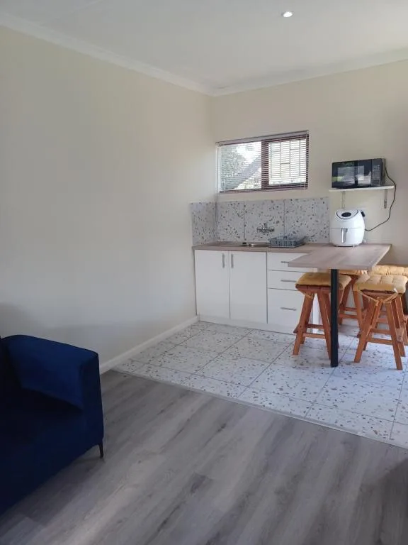 Modern kitchenette with white cabinetry, speckled backsplash, and wooden bar seating