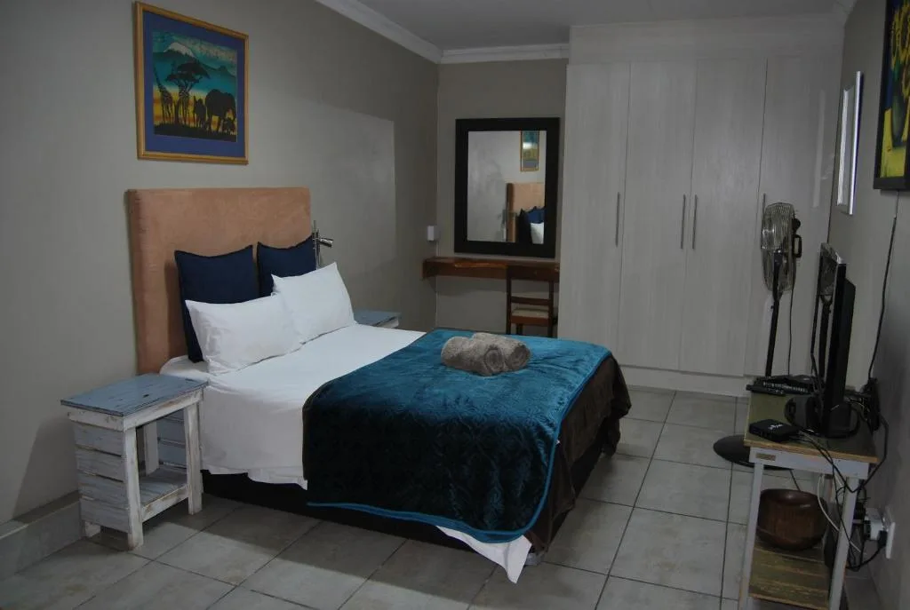 Spacious bedroom with queen bed, tan headboard, navy bedding, and mirrored vanity