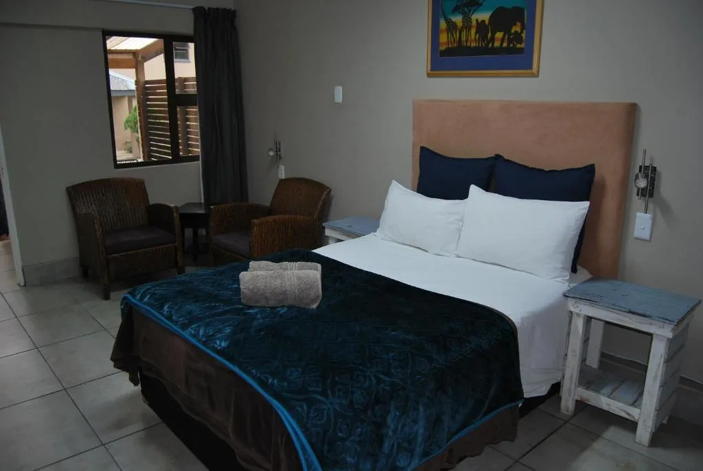 Spacious bedroom with queen bed, upholstered headboard, and seating area