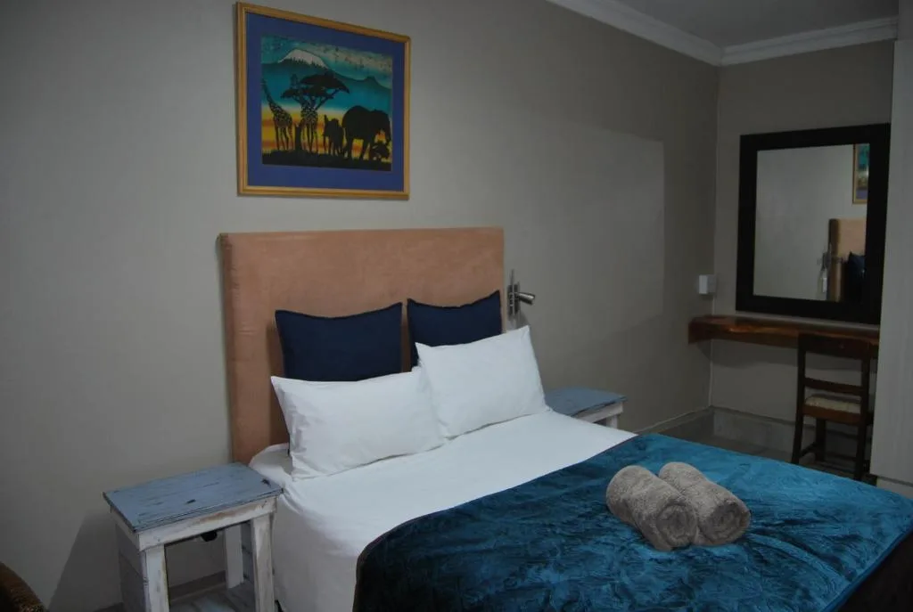 Comfortable bedroom with queen bed, neutral headboard, and African wildlife artwork