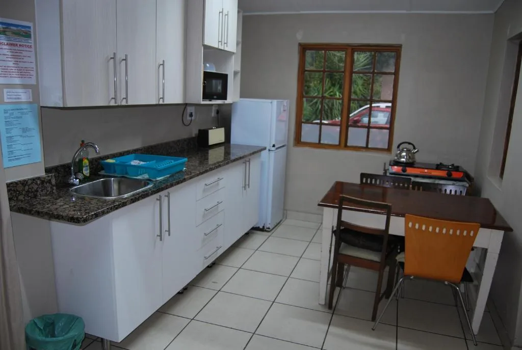 Open-plan kitchen with white cabinetry, granite countertop, and dining table seating