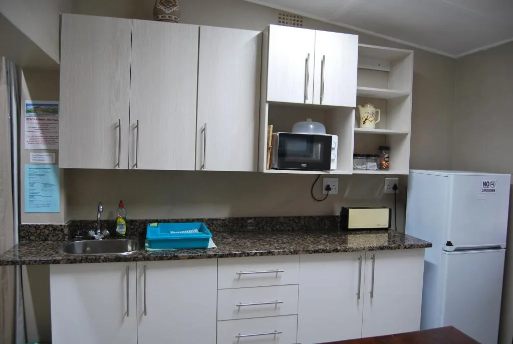 Modern white kitchen with granite countertop, microwave, and stainless appliances