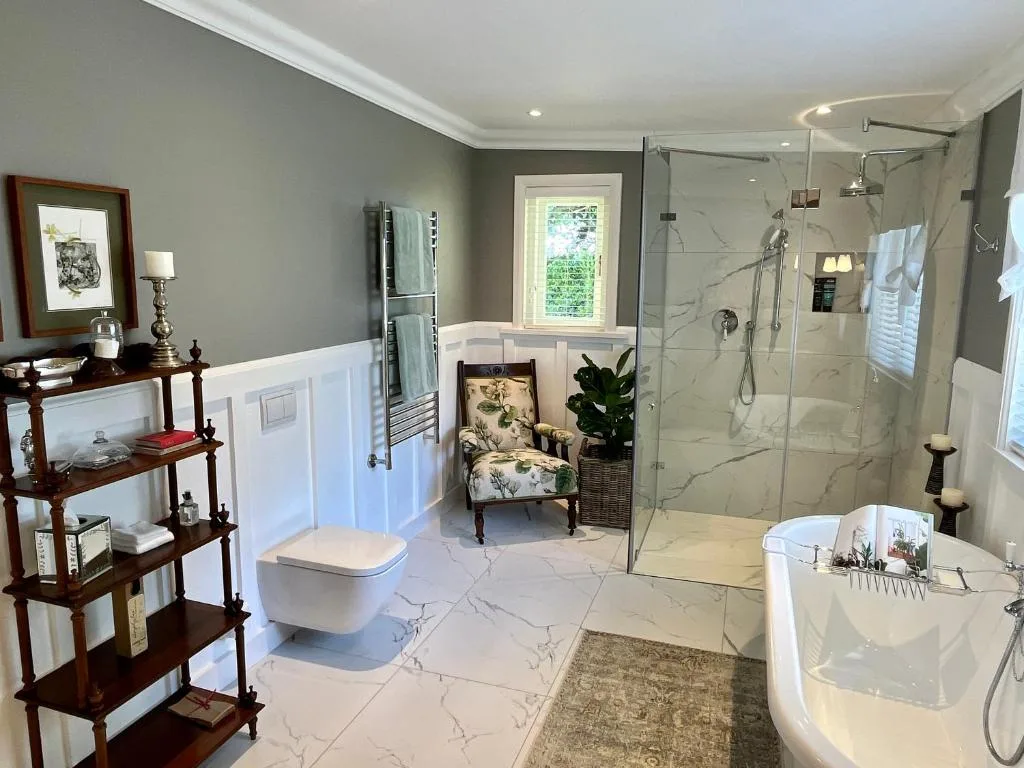 Spacious luxury bathroom with marble flooring, freestanding tub, walk-in shower enclosure