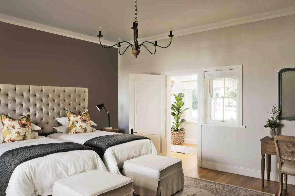 Spacious bedroom with tufted headboard, twin beds, and elegant chandelier lighting