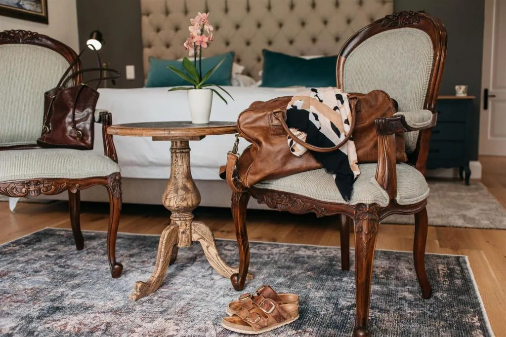 Elegant bedroom with upholstered headboard, wooden chairs, and orchid decor