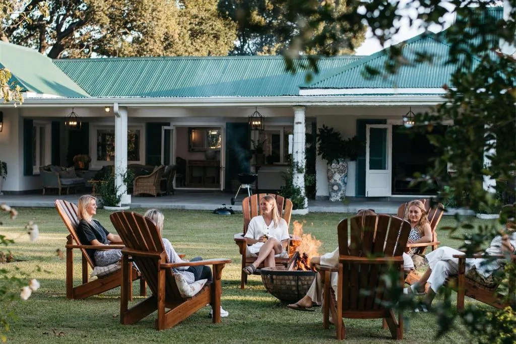 Guests relaxing in Adirondack chairs around a fire pit on the lawn
