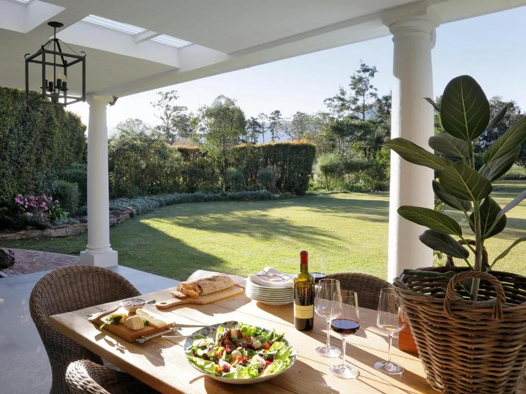 Covered patio with dining table, food, wine, overlooking manicured garden lawn