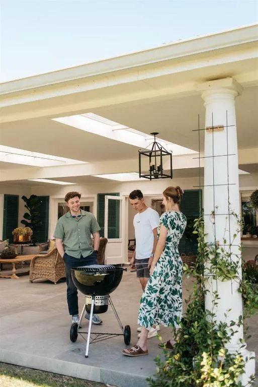 Covered patio area with guests gathered around a braai grill
