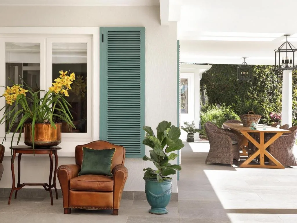 Covered patio with comfortable seating, potted plants, and garden views