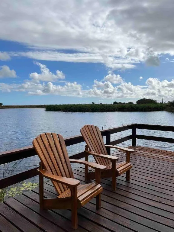 Wooden deck with Adirondack chairs overlooking lagoon and greenery