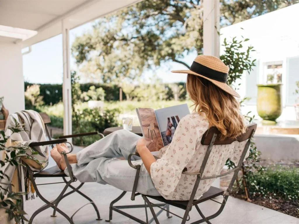 Woman relaxing in comfortable chair on covered patio with garden views