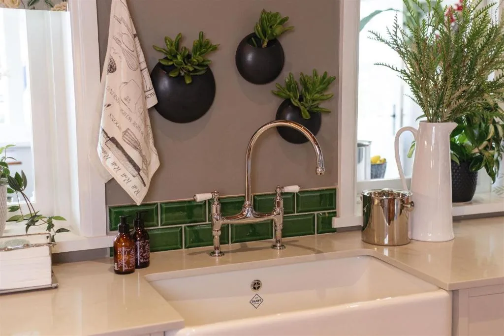 Stylish bathroom sink with green tile backsplash and hanging black planters