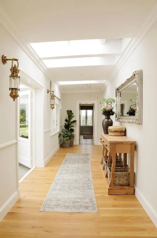 Bright hallway with skylights, wooden floors, plants, and decorative accessories