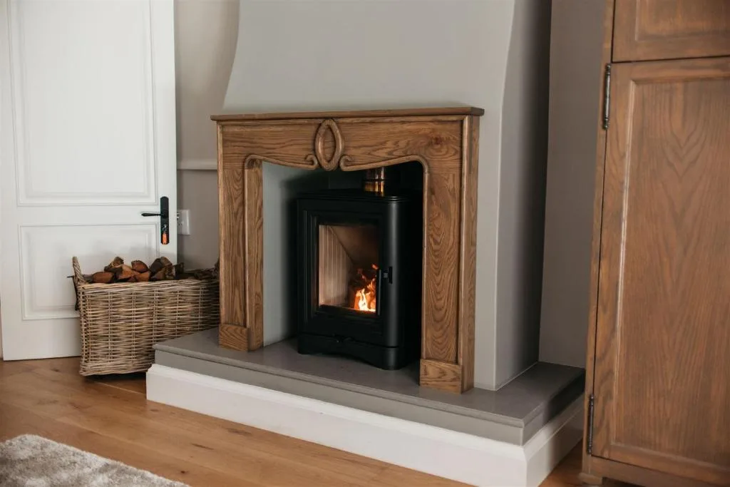 Wooden fireplace mantle with black wood-burning stove and wicker firewood basket