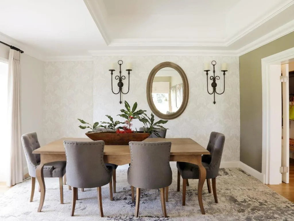 Elegant dining room with wooden table, upholstered chairs, and decorative mirror