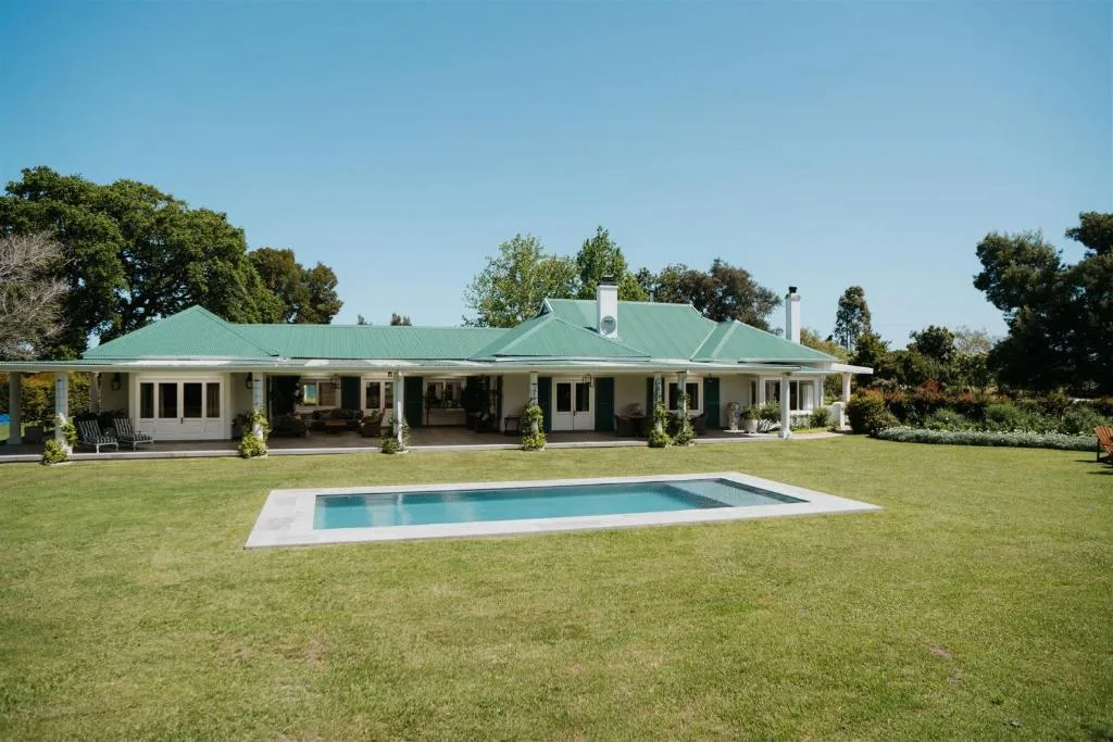 Modern villa with green roof, white walls, and rectangular pool on manicured lawn