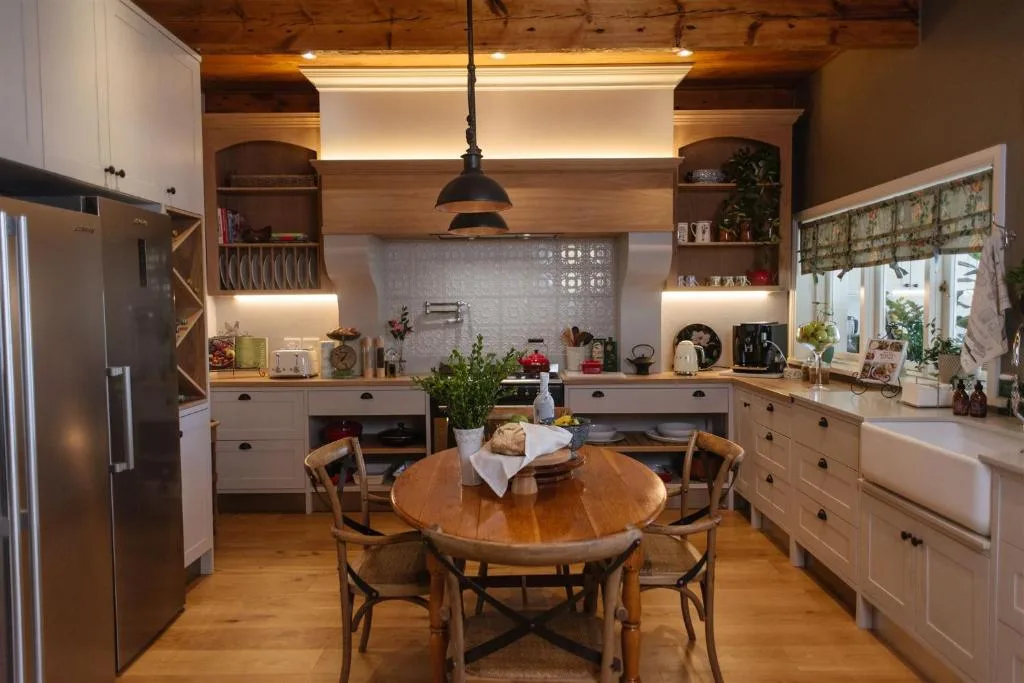 Modern kitchen with white cabinetry, wooden beams, and dining table