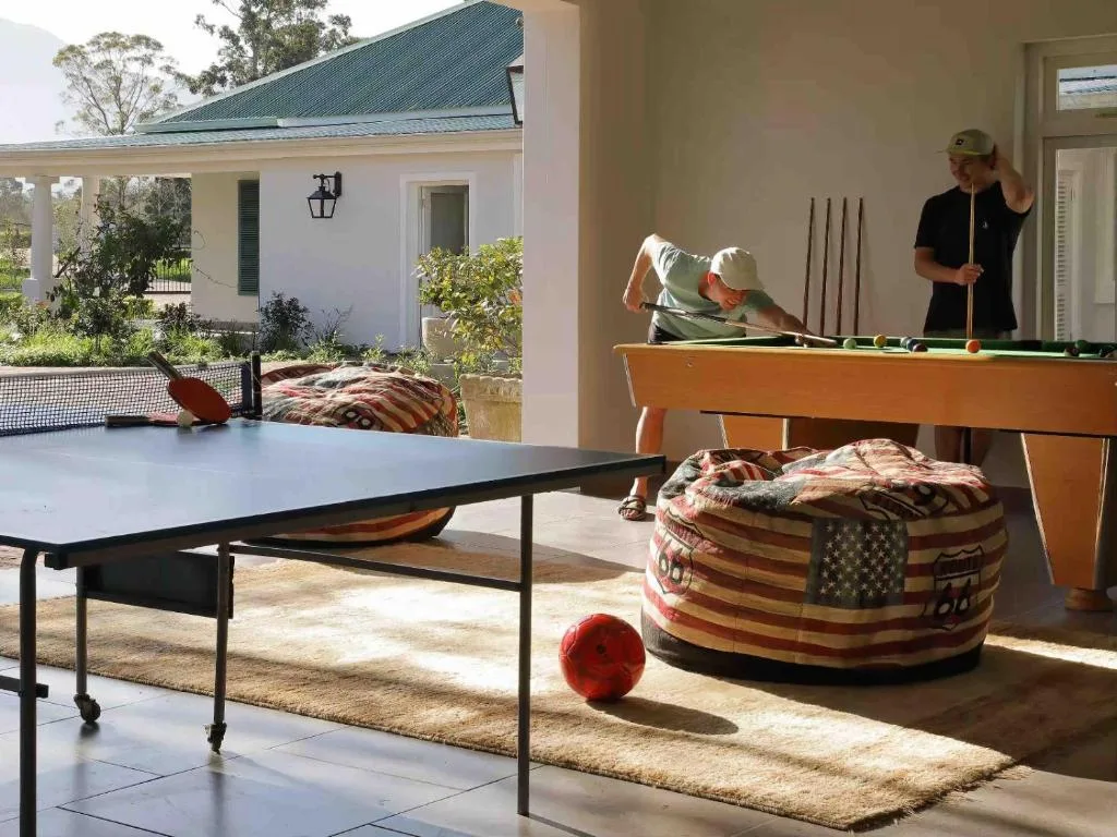 Recreation room with ping pong and pool tables, guests enjoying games indoors
