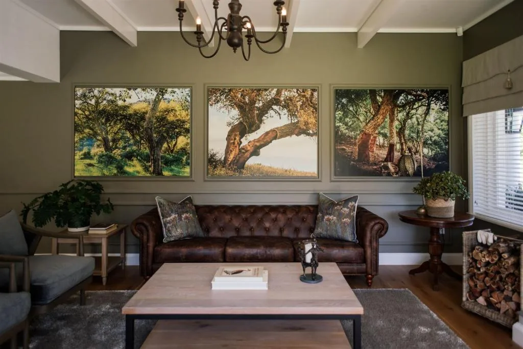Elegant lounge with brown leather sofa, tree artwork, and vintage chandelier