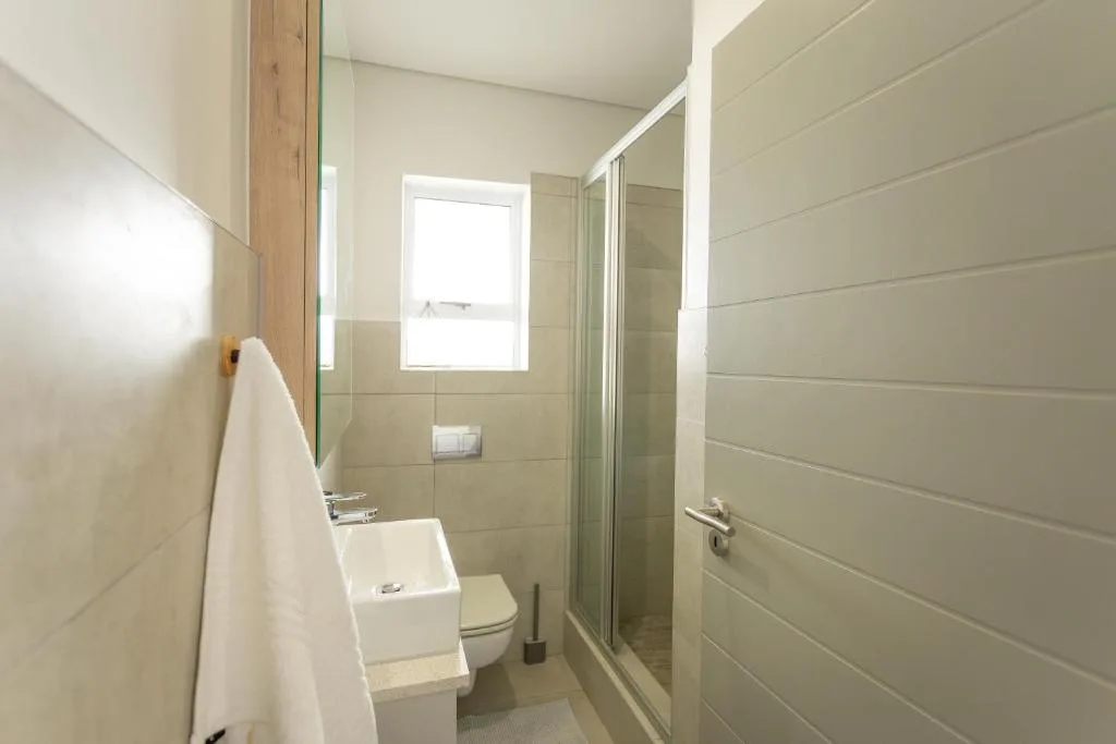 Modern bathroom with shower enclosure, toilet, and small sink vanity