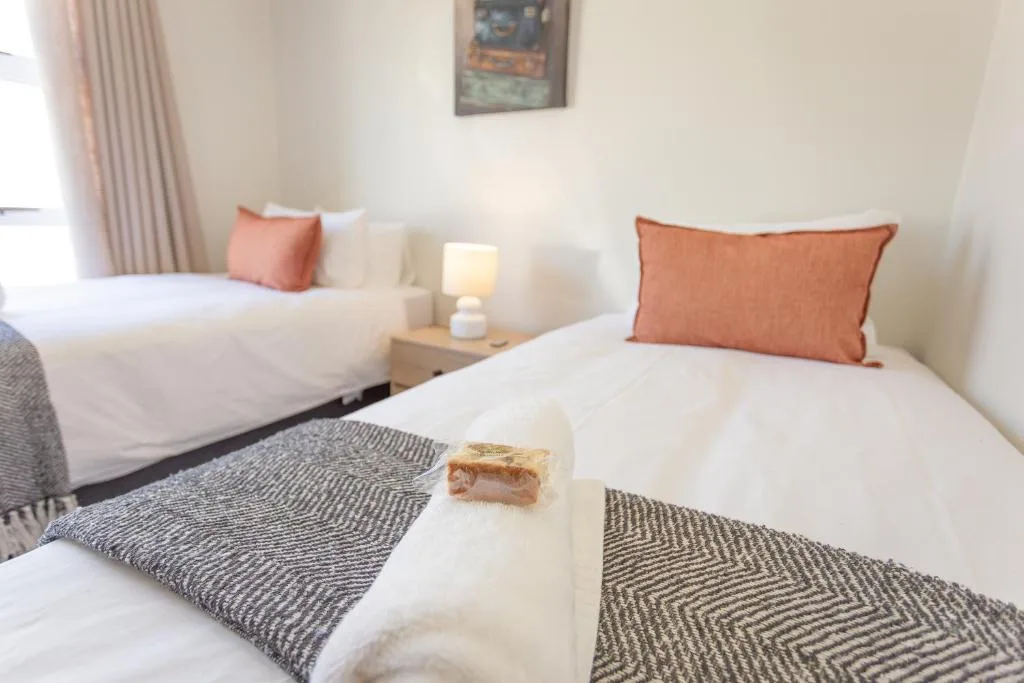 Twin bedroom with white bedding, orange accent pillows, and soft lighting
