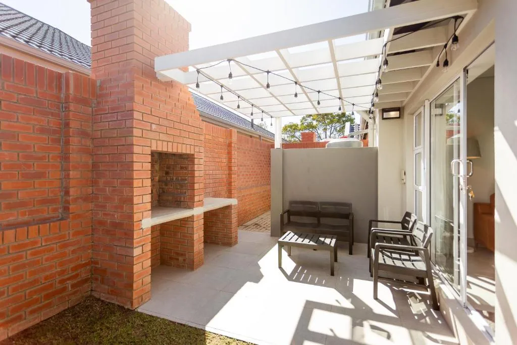 Covered patio with brick fireplace, seating, and pergola shade structure