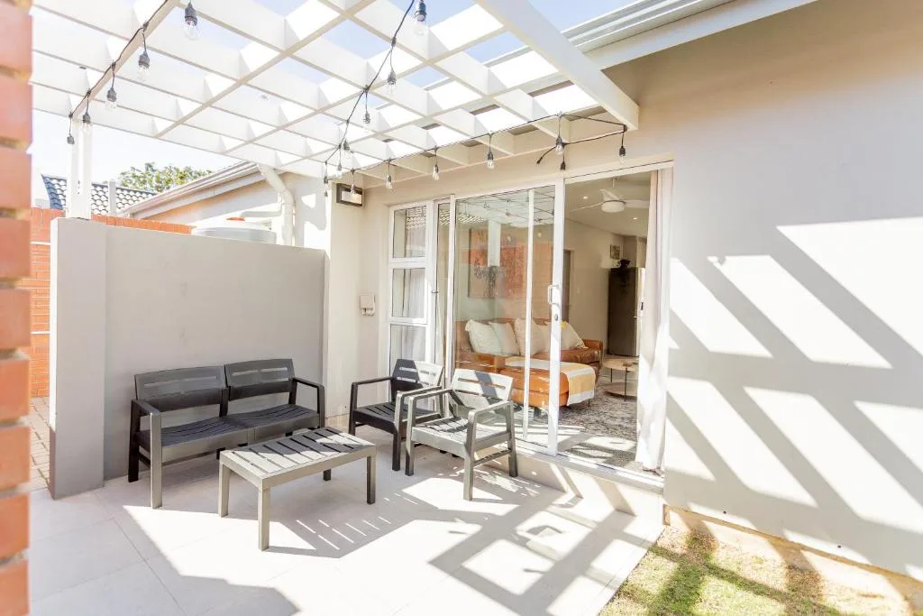 Covered patio with seating, string lights, and glass doors to interior