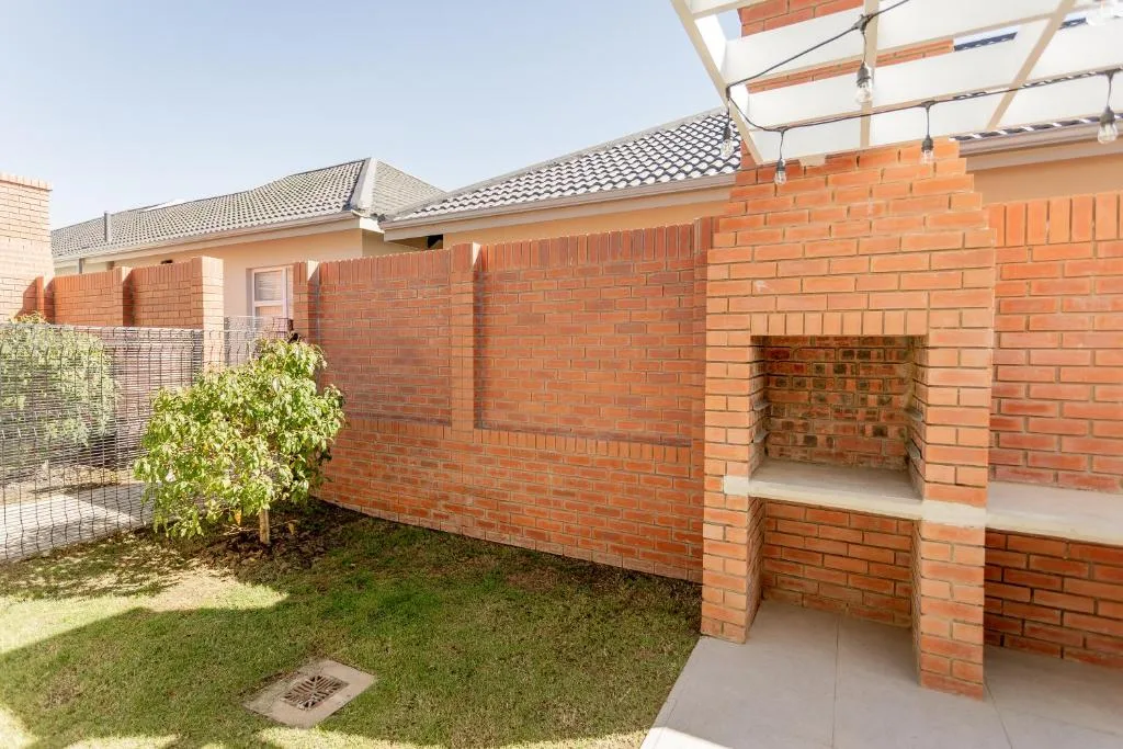 Brick patio area with built-in braai and pergola shade structure