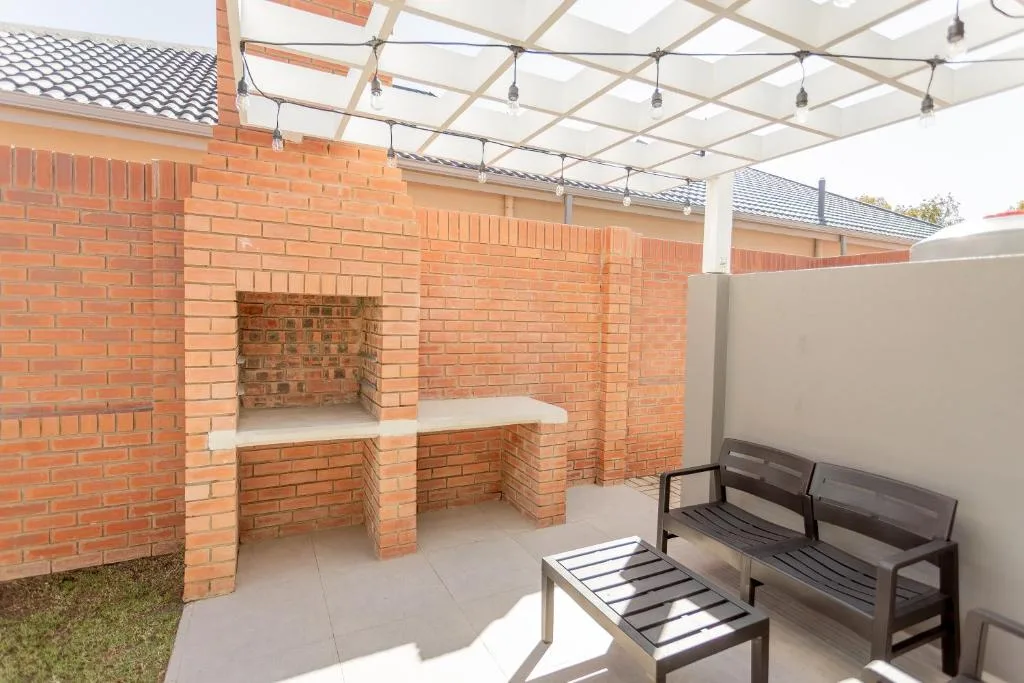 Covered outdoor patio with brick braai area and seating benches