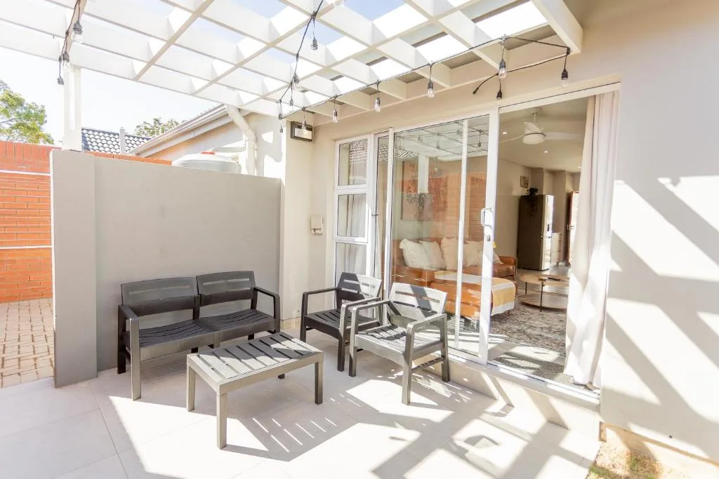 Covered patio with modern seating, pergola roof, and glass doors to interior