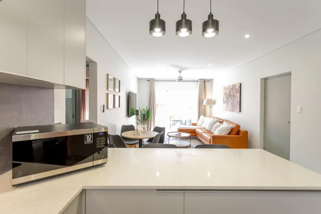 Modern open-plan kitchen with white cabinetry, microwave, and pendant lighting