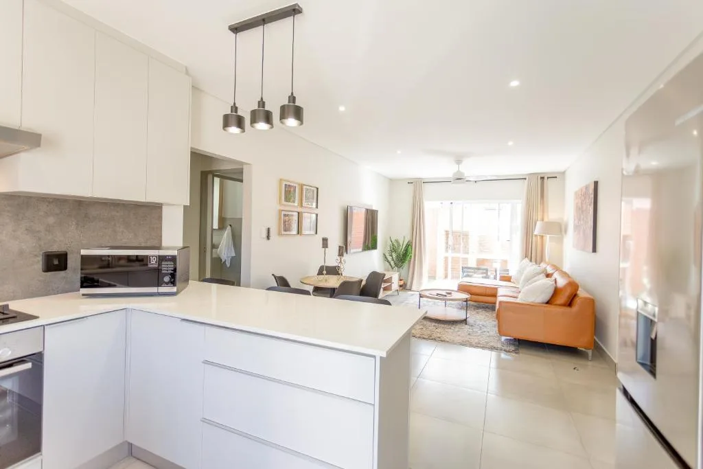 Modern white kitchen with island bench overlooking open plan lounge area