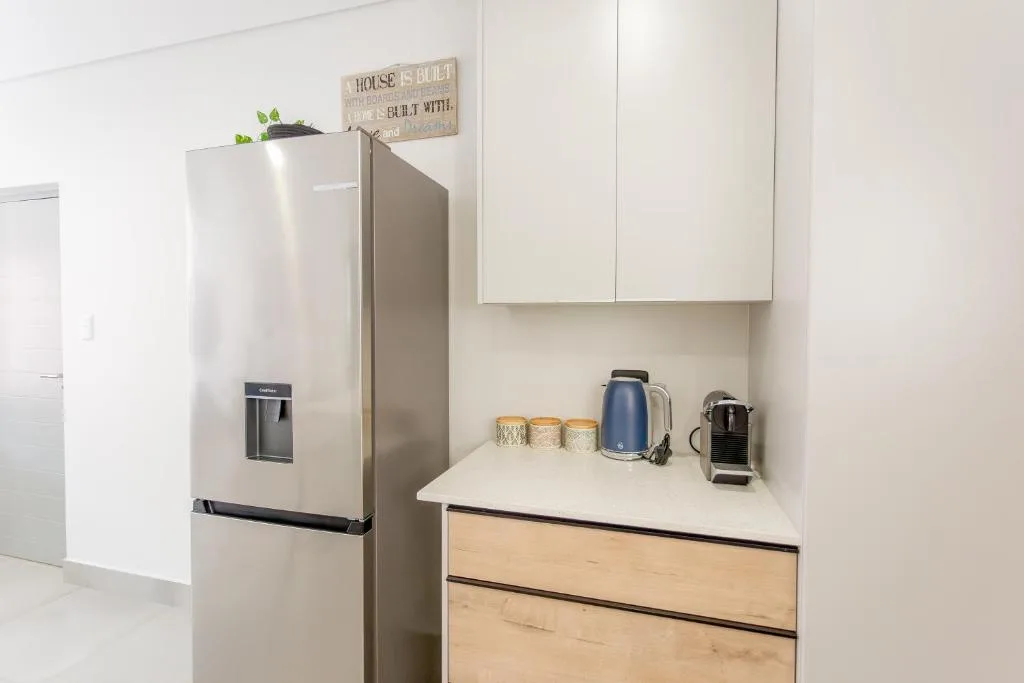 Modern kitchen with stainless steel refrigerator and white cabinetry