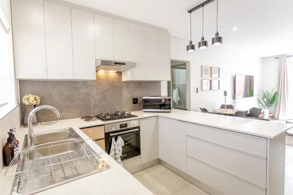 Modern white kitchen with gas stove, sink, and pendant lighting overhead