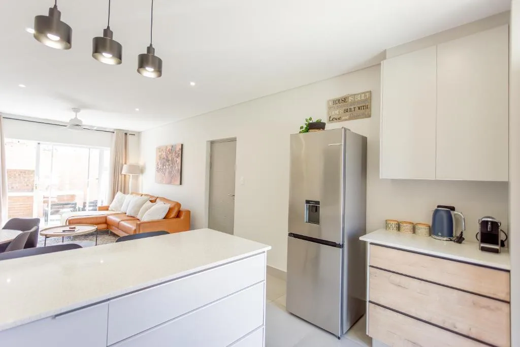 Modern kitchen with white cabinetry, stainless steel fridge, pendant lighting, island counter