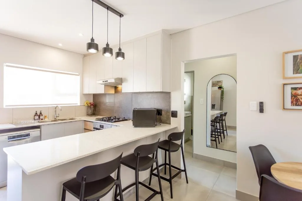 Modern kitchen with white cabinetry, island seating, and pendant lighting fixtures