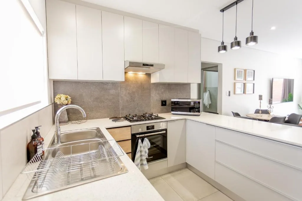 Modern white kitchen with stainless steel appliances and gray tile backsplash