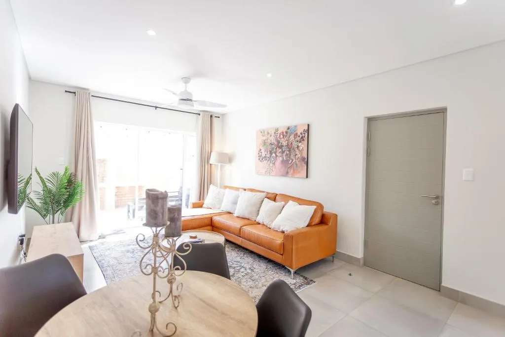 Modern lounge with cognac leather sofa, dining table, TV, and ocean views