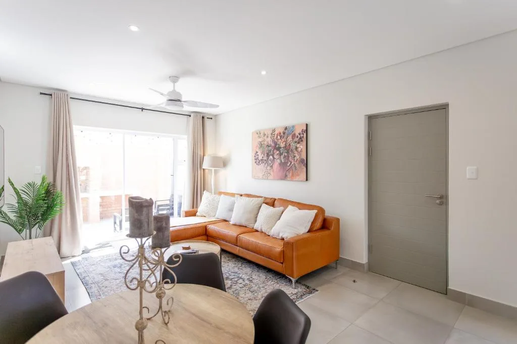 Bright living room with orange leather sofa and white cushions overlooking balcony